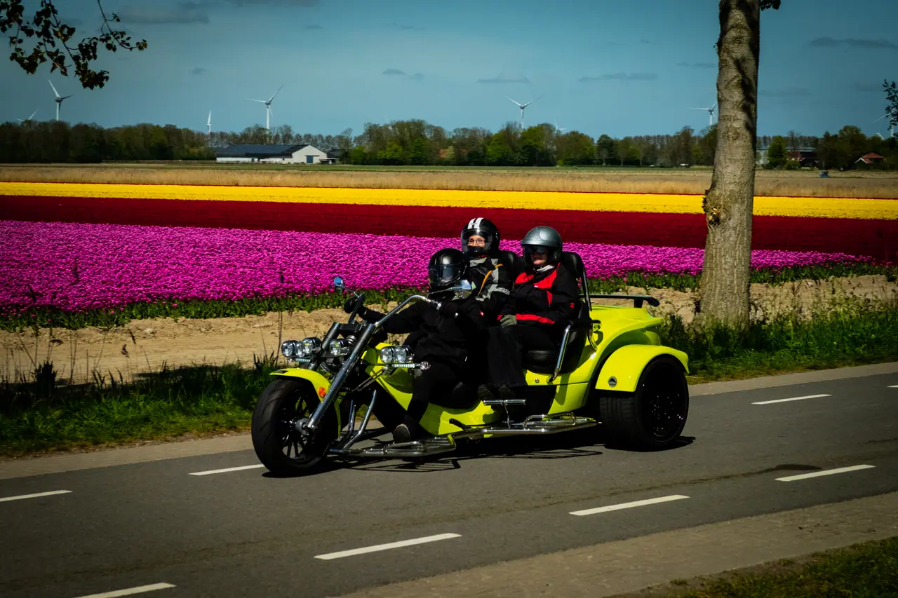 Trikerijders zwaaien tijdens een rit door de bollenvelden