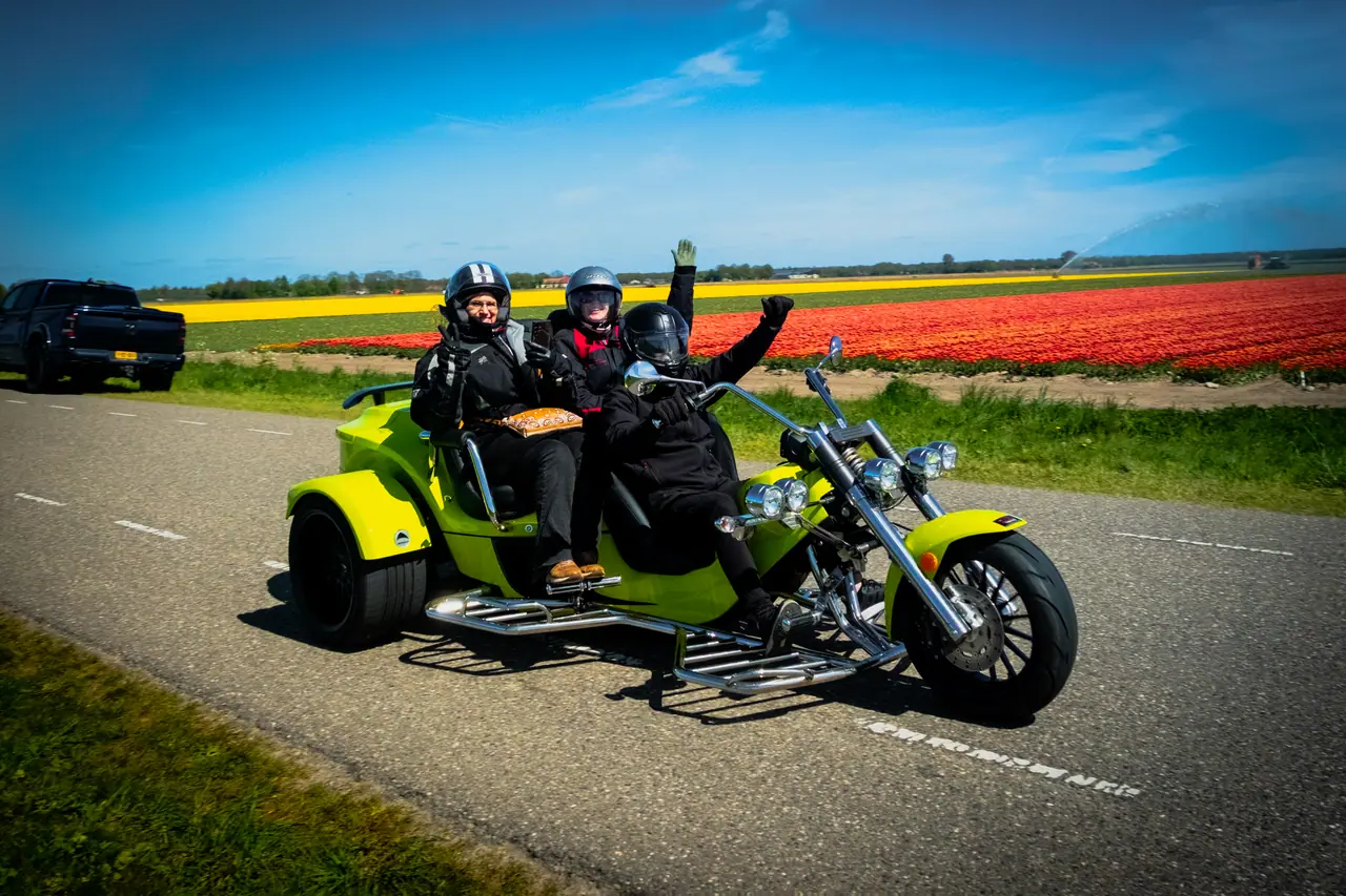 Lachende trikerijders tijdens een rit langs de bollenvelden